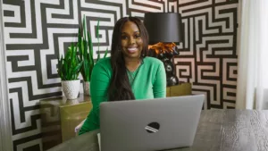 femme souriante derrière un ordinateur pour illustrer le bien-être au travail dans son entreprise