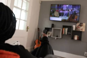 Femme devant un écran de tv, la télécommande à la main